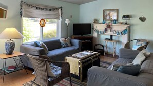 A living room with a sofa, chairs, a table, a television, and a fireplace. - 3BD/2BA, Walkable, Family/Dog Friendly, Deck, BBQ, WIFI in Quaint Rockaway Beach (Rockaway Beach)