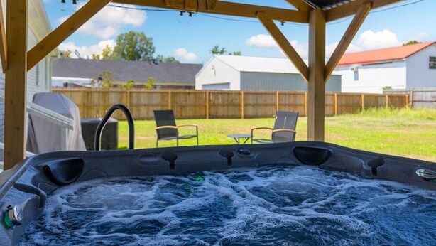 A hot tub with a wooden deck and chairs in the background.