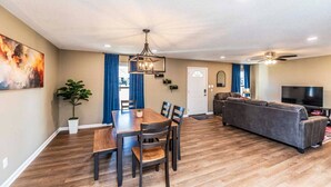 A spacious living area with a dining table, sofa, and TV.