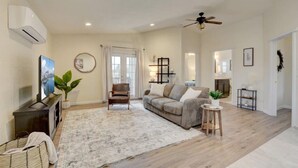 A spacious living room with a grey sofa, a wooden coffee table, a TV, and a ceiling fan. - Beautiful Loft Apartment w/Views in Medford, OR! (Medford)