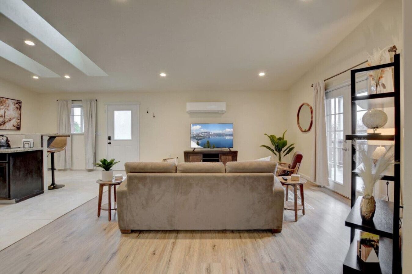 Un salón moderno con un sofá color beige, un televisor de pantalla plana y una mesa de centro de madera.