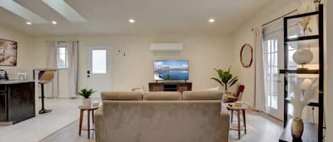 A modern living room with a beige sofa, a flat-screen TV, and a wooden coffee table.