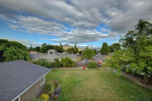 A residential area with houses, a grassy yard, and a hilly landscape in the background.