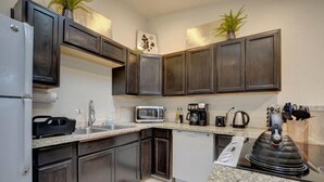 A modern kitchen with dark wood cabinets, granite countertops, a built-in microwave, a coffee maker, and a kettle. - Beautiful Loft Apartment w/Views in Medford, OR! (Medford)