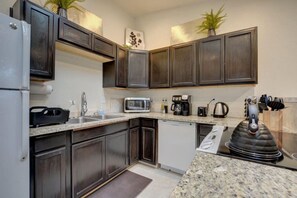 A modern kitchen with dark wood cabinets, granite countertops, a built-in microwave, a coffee maker, and a kettle. - Beautiful Loft Apartment w/Views in Medford, OR! (Medford)