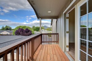 A wooden deck with a view of a residential neighborhood and mountains in the background.