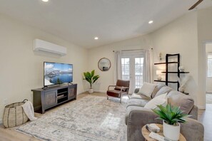 A living room with a flat-screen TV, a sofa, a chair, a coffee table, and a potted plant. - Beautiful Loft Apartment w/Views in Medford, OR! (Medford)