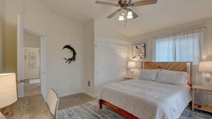 A bedroom with a bed, a ceiling fan, a door, and a nightstand with a lamp. - Beautiful Loft Apartment w/Views in Medford, OR! (Medford)
