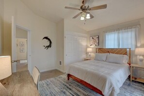 A bedroom with a bed, a ceiling fan, a door, and a nightstand with a lamp. - Beautiful Loft Apartment w/Views in Medford, OR! (Medford)