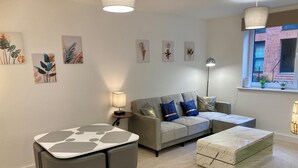 Una sala moderna con un sofá gris, una mesa de comedor con sillas y una mesa de centro de mármol.