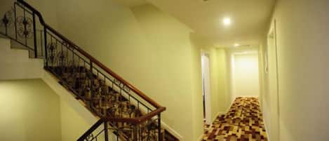 A staircase with a wooden handrail and black metal railing, leading to a room with a checkered floor.