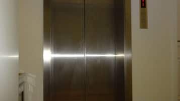An elevator with a metallic finish and a digital display on the wall.