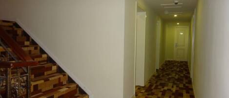 A hallway with a wooden staircase on the left and a patterned carpet.