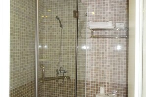 A shower with a glass door, tiled walls, and a shelf with towels. - Yuejia Hotel (Shanghai Minhang Jiaoda) (Shanghai)