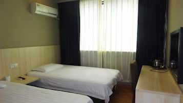 Quarto de hotel com duas camas, uma escrivaninha de madeira, televisão e janela com cortinas.