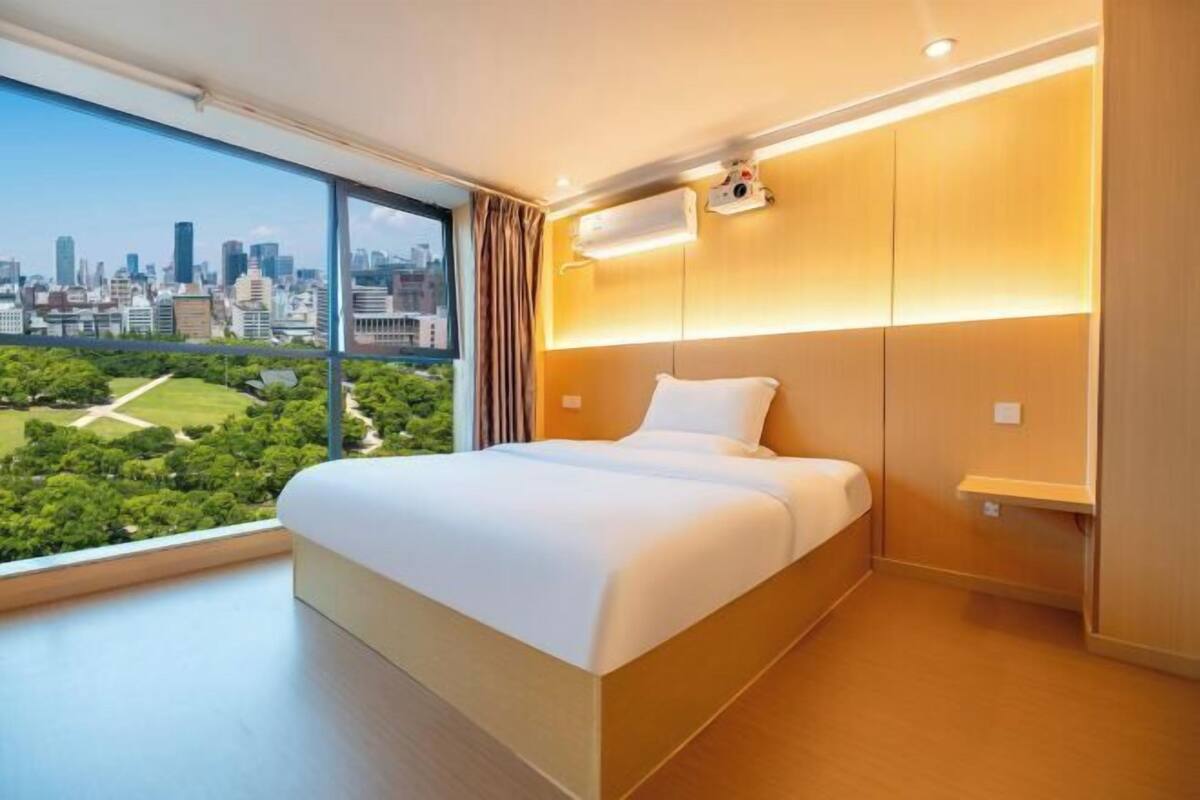 Een moderne hotelkamer met een groot bed, uitzicht over de stad en een ingebouwde airconditioning.
