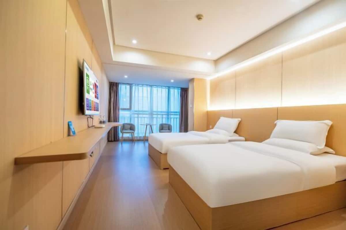 Een hotelkamer met twee bedden, een televisie, een bureau en een raam met gordijnen.