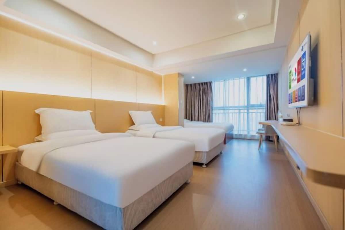 Een hotelkamer met twee bedden, een televisie aan de muur en een groot raam.