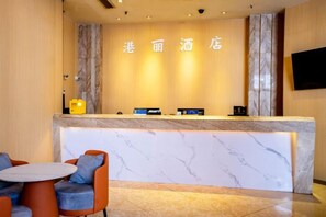 A hotel reception area with a marble counter, seating, and a television mounted on the wall. - Chongqing Gangli Hotel (Nanping Convention and Exhibition Center Branch) (Chongqing)