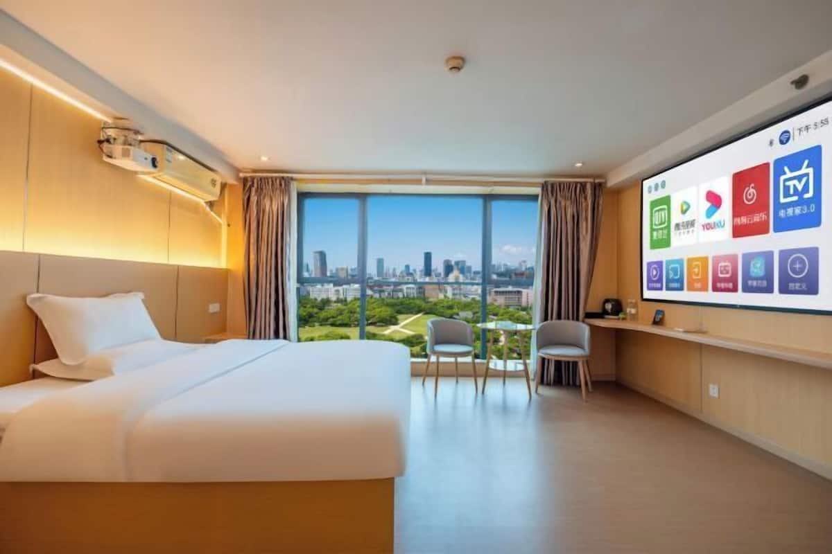Een hotelkamer met een groot bed, een bureau en een televisie waarop verschillende apps worden getoond.