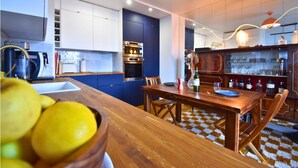 Una cucina moderna con un tavolo da pranzo in legno, forno integrato e angolo bar con bicchieri.