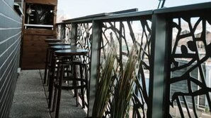 A balcony with a wooden table and chairs, a potted plant, and a metal railing. - L'Échappée Parisienne - Canal St-Denis (Aubervilliers)