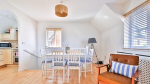 Una cocina moderna con armarios blancos, un microondas y un comedor con mesa y sillas.
