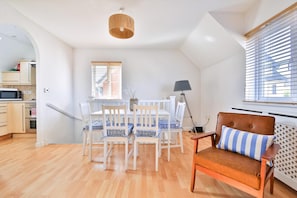 A modern kitchen with white cabinets, a microwave, and a dining area with a table and chairs. - 2 Bed House Near Beach with Free Parking (Barry)