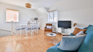 Un espacio habitable amplio con una mesa de comedor, un sofá, un televisor y un ventilador de techo.