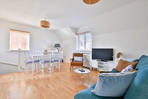 A spacious living area with a dining table, a sofa, a TV, and a ceiling fan. - 2 Bed House Near Beach with Free Parking (Barry)