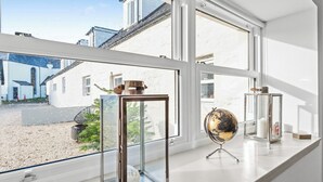 Ett modernt rum med stora fönster, en jordglob och dekorativa glasföremål.