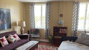A cozy living room with a sofa, a coffee table, a bed, and a bookshelf.
