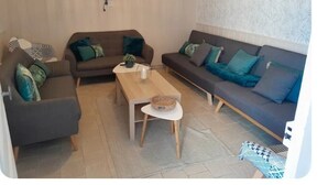 A living room with two sofas, a coffee table, and a TV mounted on the wall. - Le Paradis near Beauval. (Orbigny)