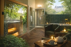 A spa area with a hot tub, glass doors, a shower, and a seating area with candles. - RELAI DU CHATEAU DE LA TOURLANDRY (Chemillé-en-Anjou)