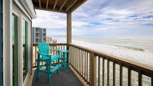 A wooden deck with a view of the ocean, two turquoise chairs, and a table. - Oceanfront Bliss: Sand and Views at Watchin' Waves (North Topsail Beach)