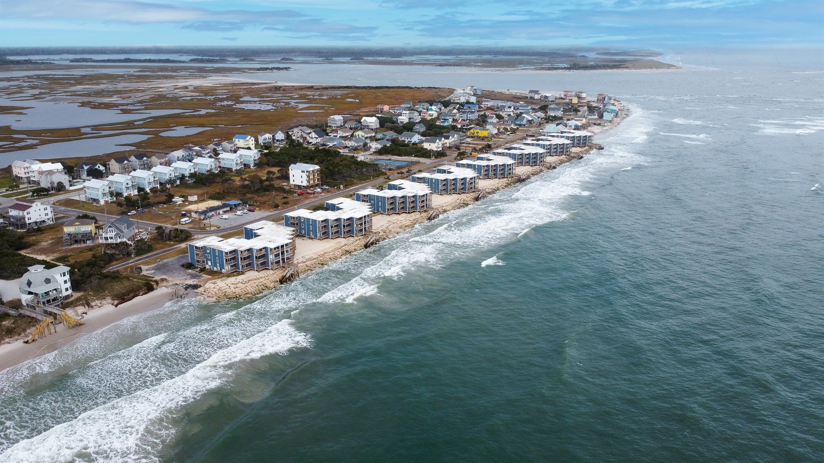 A coastal residential area with beachfront properties, including multi-story buildings and single-story homes.