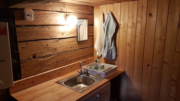 A wooden cabin bathroom with a sink, a mirror, and a towel hanging on the wall. - Hut for skiing or hiking (Pill)