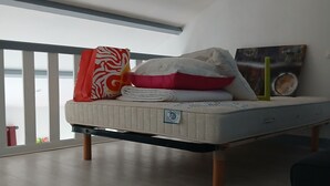 A bedroom with a bed, pillows, a blanket, and a painting on the wall. - Small house by the sea Pets welcome (Pornic)