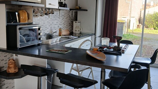 A modern kitchen with a central island, bar stools, and a view of the outdoors. - Small house by the sea Pets welcome (Pornic)