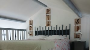 A bedroom with a bed, a nightstand, a lamp, and a window. - Small house by the sea Pets welcome (Pornic)