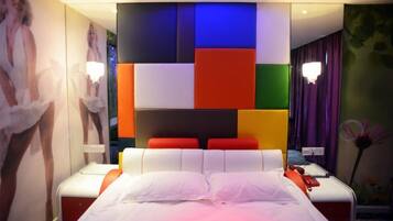 Een moderne hotelkamer met een groot bed, een nachtkastje en een muur met kleurrijke geometrische patronen.