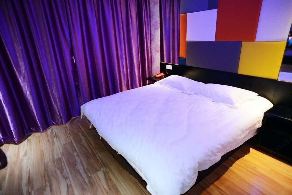 Une chambre d’hôtel moderne avec un grand lit, un plancher en bois et un panneau mural aux couleurs vives.