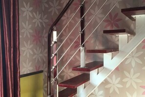 A staircase with a metal handrail and wooden steps, leading to an upper floor.