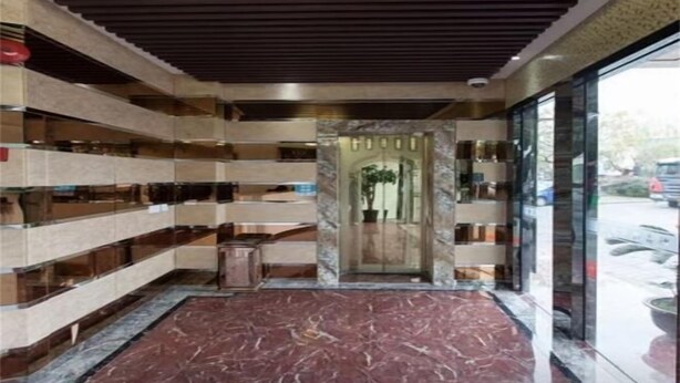 Un hall d’entrée doté d’un sol en marbre, d’un plafond en bois et d’étagères où sont exposés divers objets.