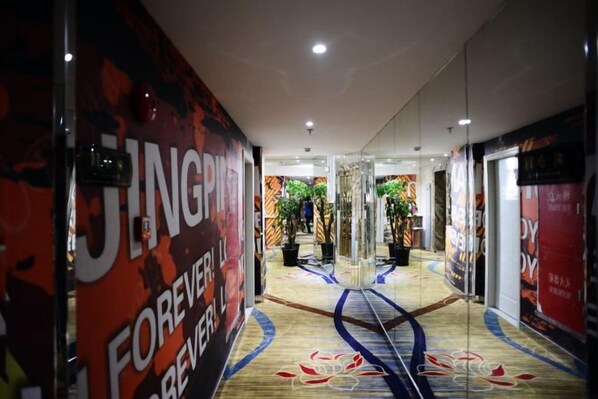 A hotel corridor with mirrored walls, a patterned carpet, and a central plant. - Yijia Boutique Hotel (Shanghai)