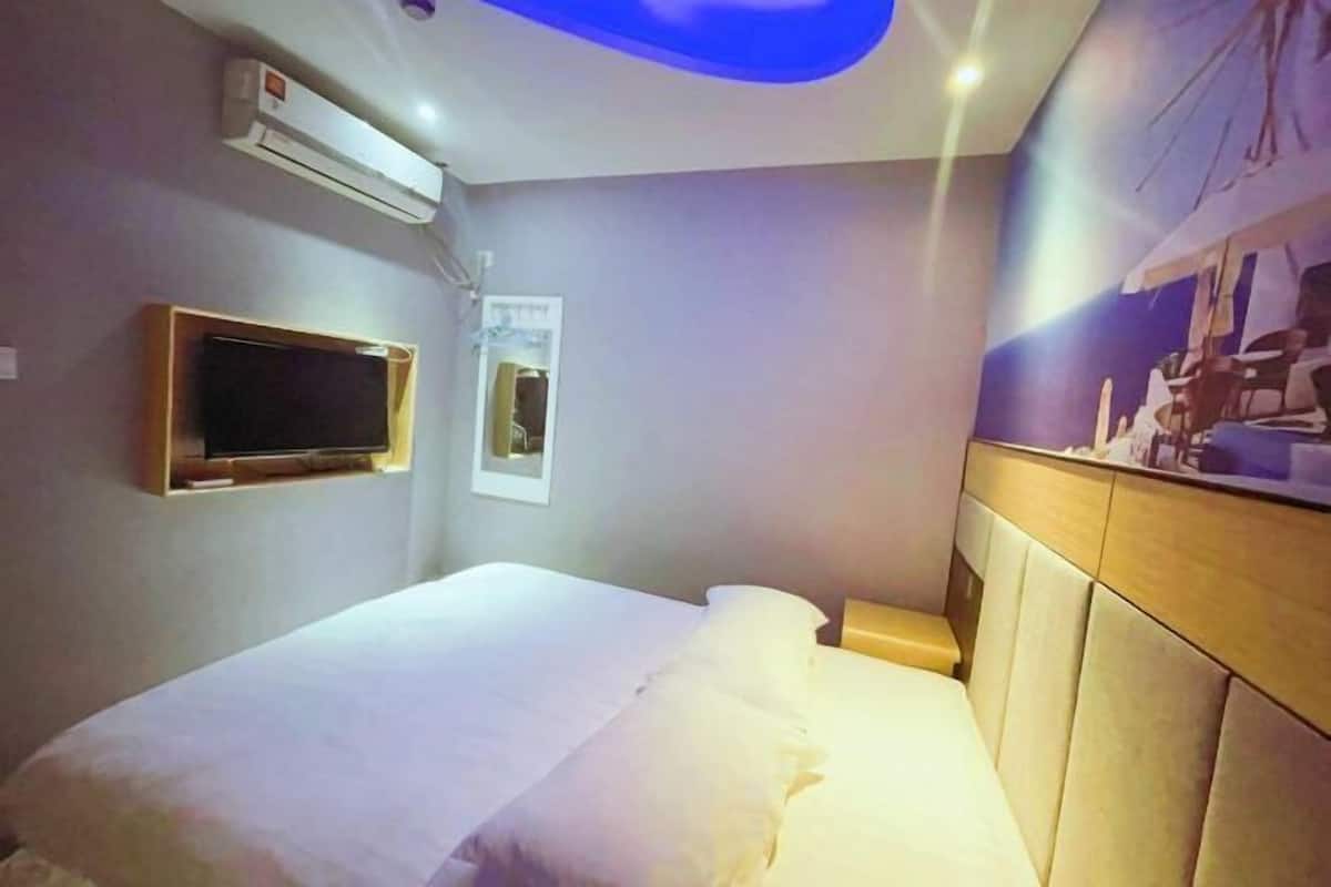 Une chambre d’hôtel équipée d’un lit, d’un téléviseur fixé au mur, d’un appareil de climatisation et d’une œuvre d’art accrochée au mur.