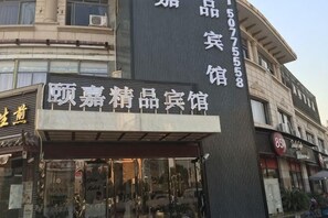A building with a storefront labeled '顾嘉精品宾馆' and a contact number '507555858'. - Yijia Boutique Hotel (Shanghai)