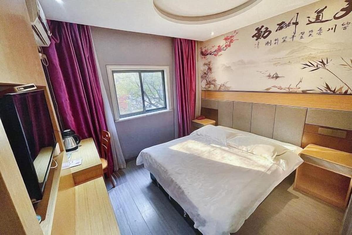 Une chambre d’hôtel comprenant un lit, un bureau, une chaise, une fenêtre et un mur décoré d’œuvres d’art.