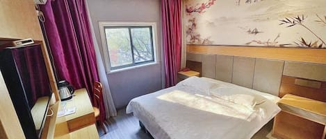 Une chambre d’hôtel comprenant un lit, un bureau, une chaise, une fenêtre et un mur décoré d’œuvres d’art.