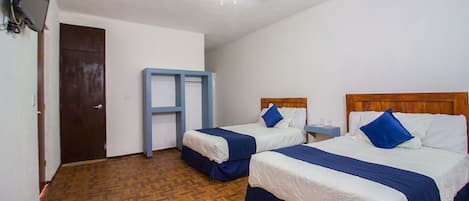 A hotel room with two beds, a ceiling fan, a wooden floor, and a small table with a nightstand.